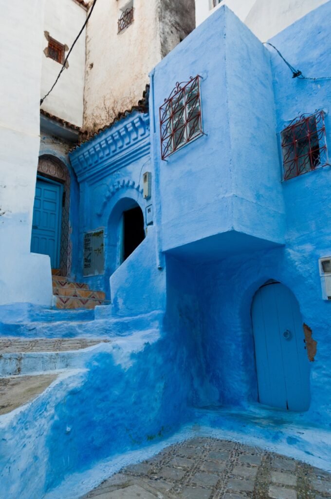 A narrow blue-painted street in the medina of Chefchaouen, Morocco's Blue City, a common final stop on a northern loop road trip itinerary