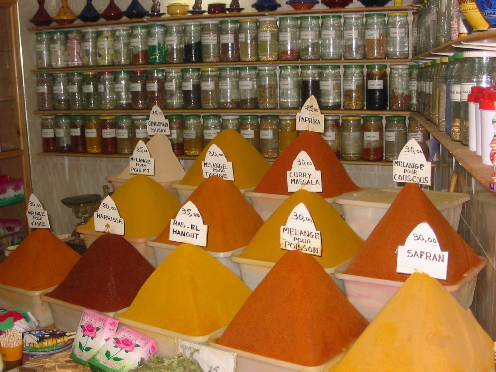 Cones of colorful ground spices including paprika, turmeric, and cumin displayed at a spice stall in a Moroccan souk