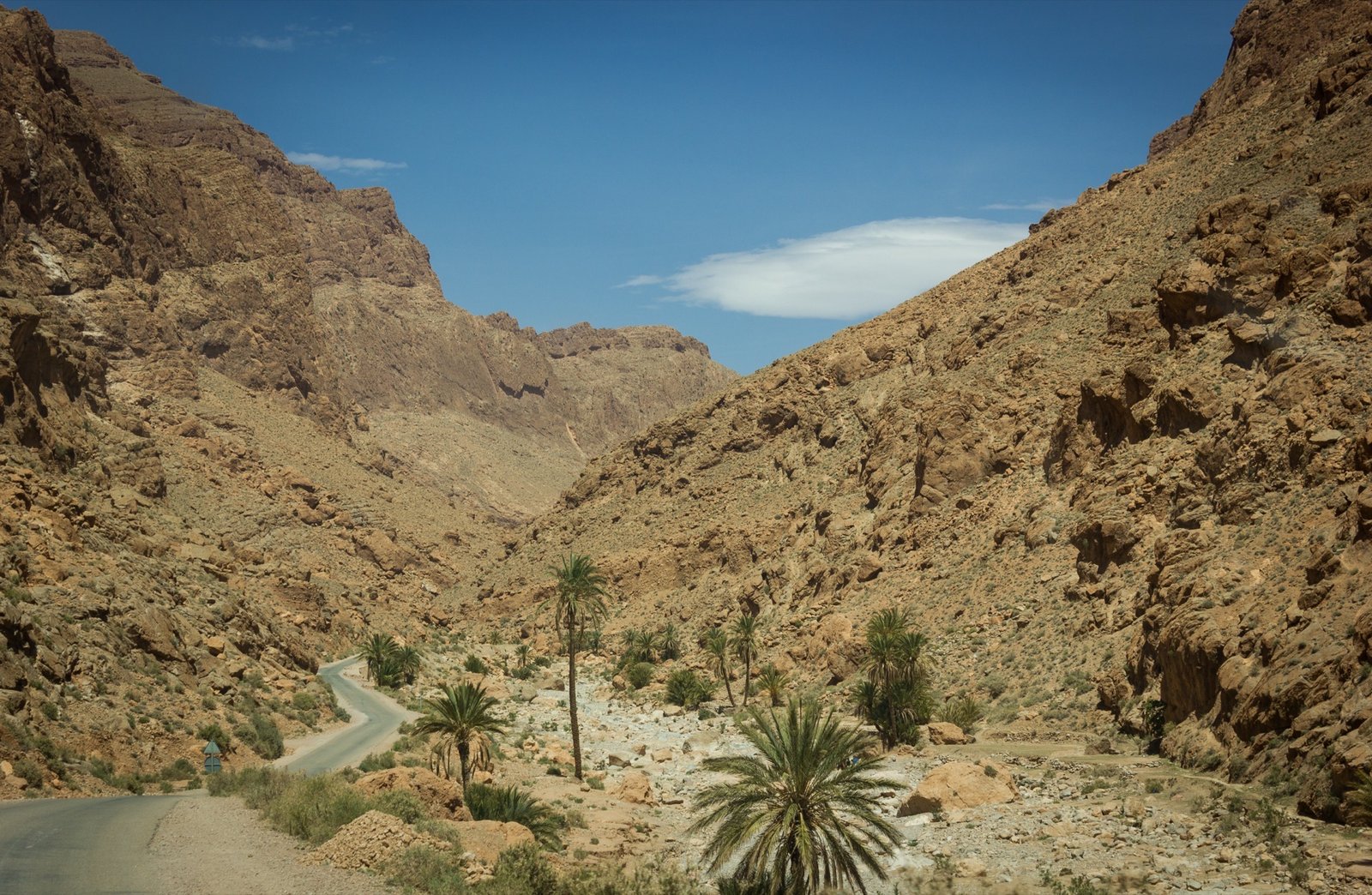 The narrow road running through the base of Todra Gorge between its towering limestone walls, part of the route between Ouarzazate and the Sahara near Merzouga